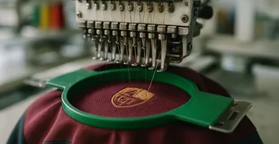 Stickmaschine bestickt ein Musterteil mit dem Kundenlogo