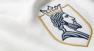 Gesticktes Wappen in Marine und Gold auf weißem Piqué