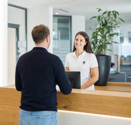 Mitarbeiterin am Empfang im weißen Polo mit gesticktem Logo
